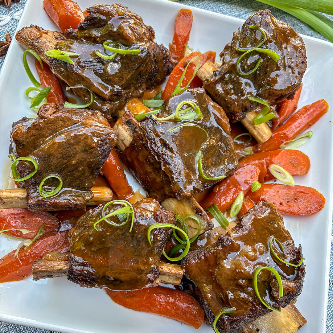 Braised lamb ribs with carrots on a white plate